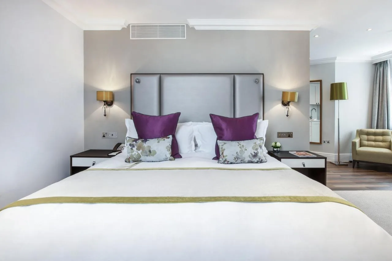 Bedroom with a large white bed and purple pillows at St. James' Court, A Taj Hotel, London